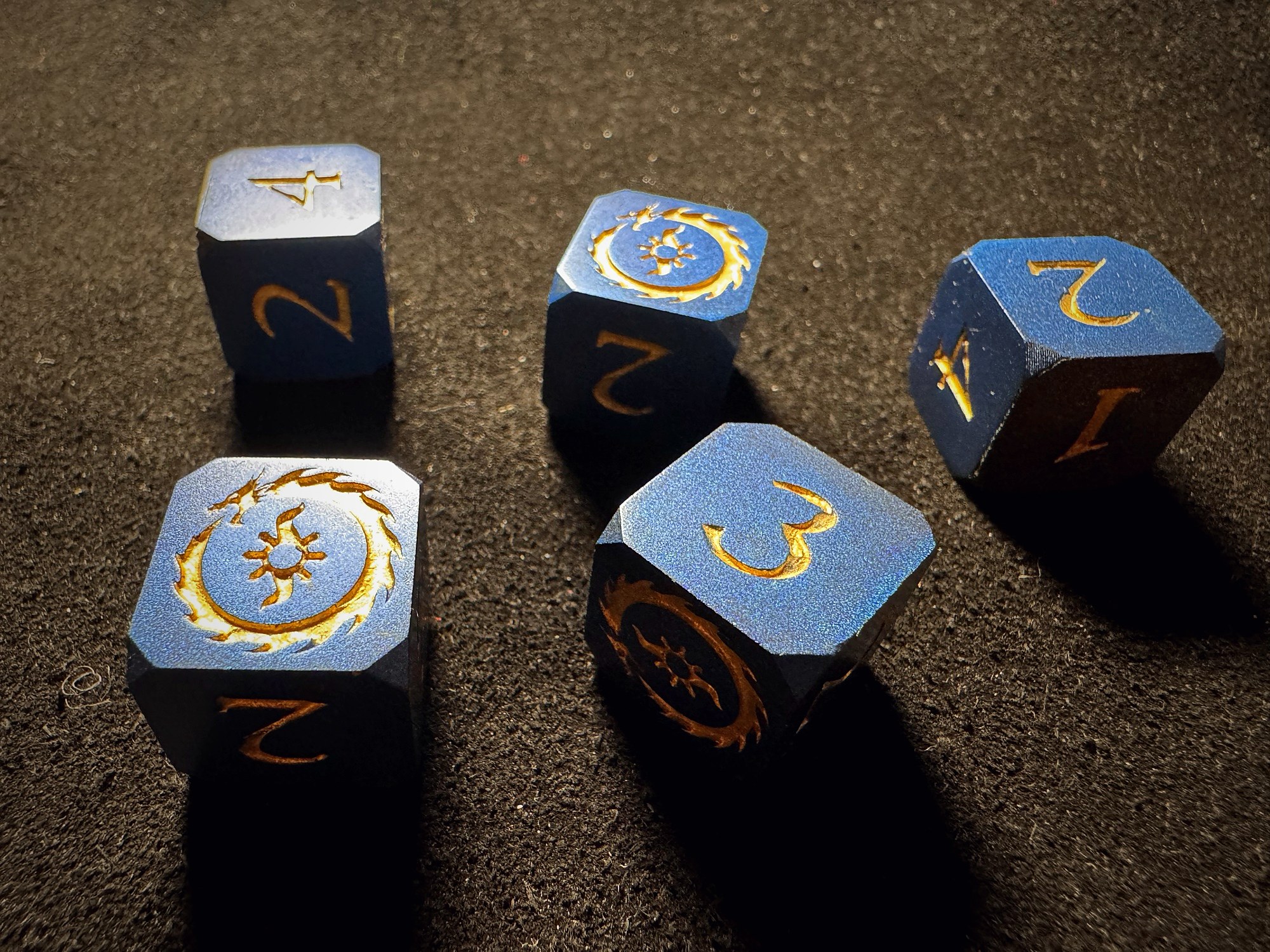 Blue composite dice with gold-engraved arcane sigils on dark textured surface