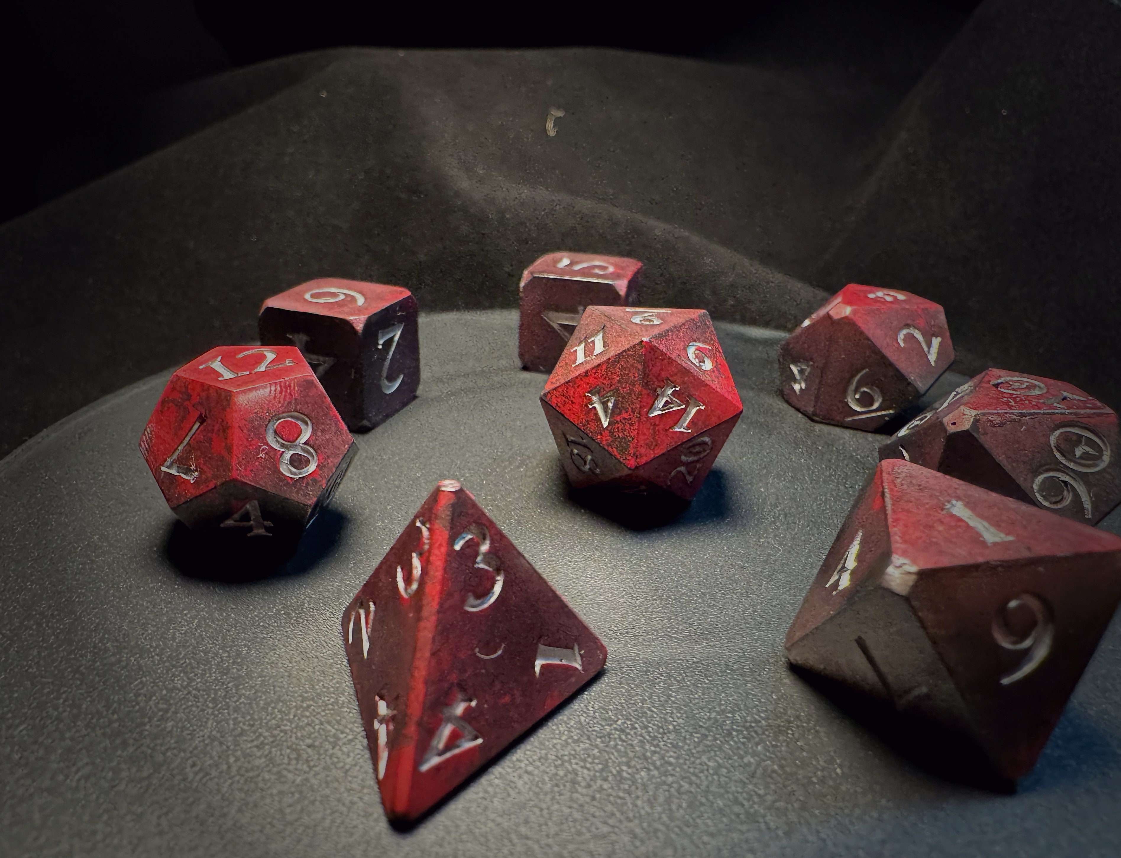 Complete set of red and black composite dice viewed from overhead on dark velvet surface