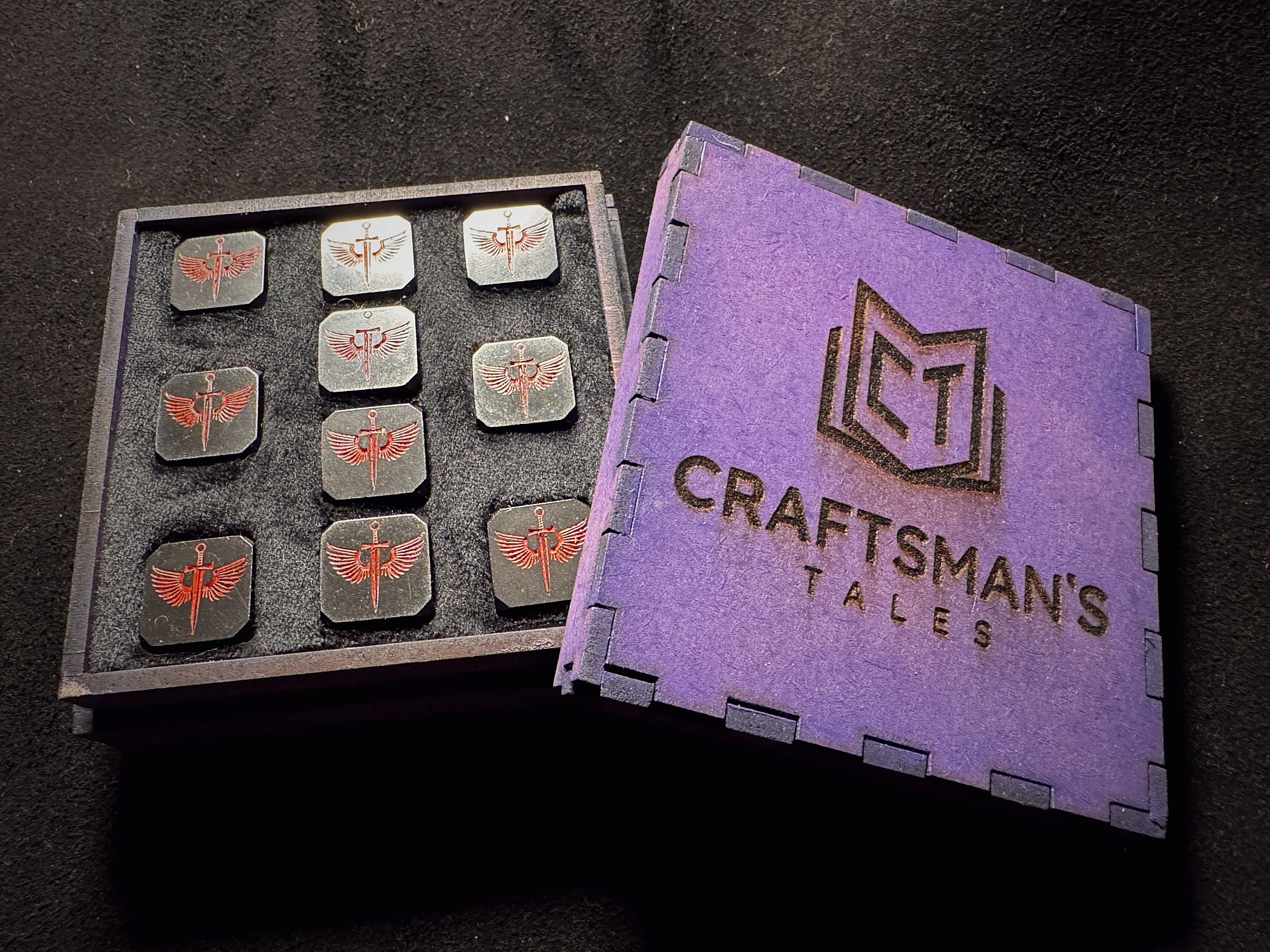 Iridescent engraved metal stamps with arcane designs arranged in a custom Craftsman's Tales box