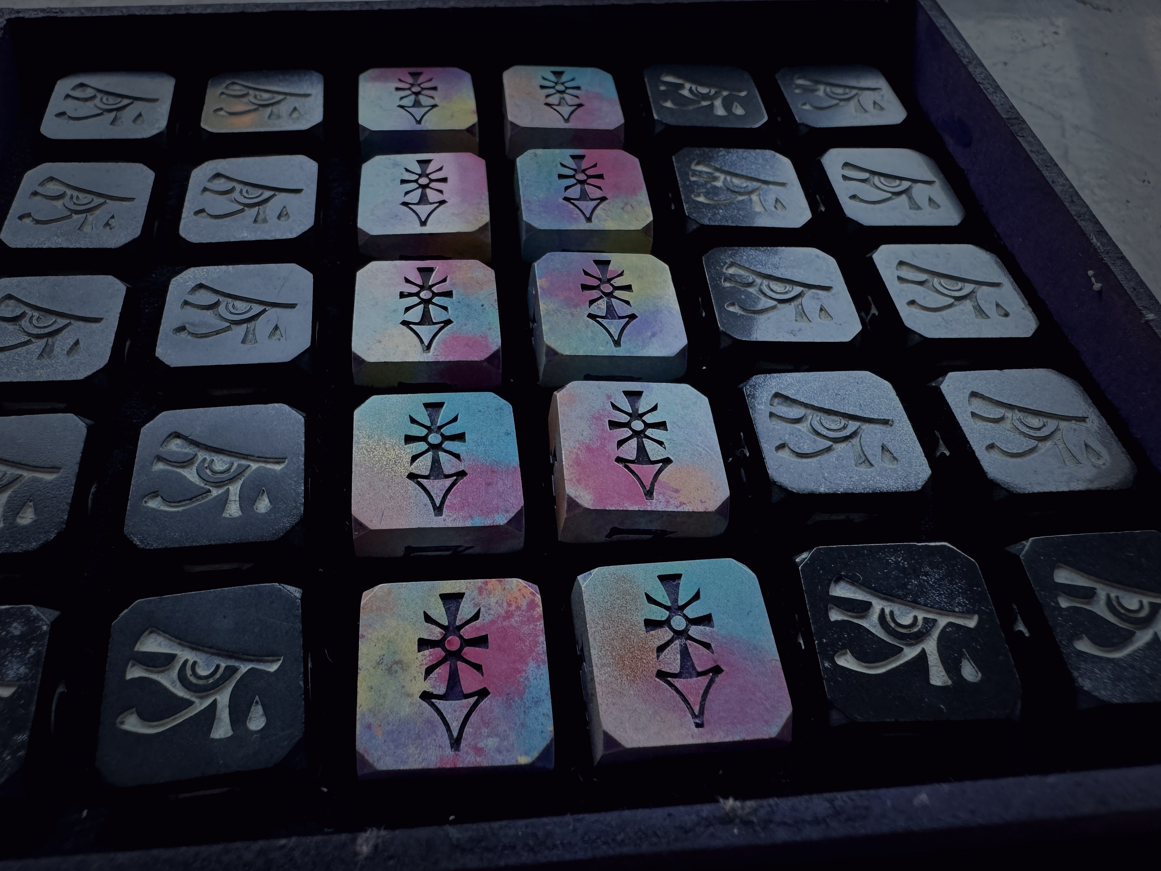 Close-up of iridescent rainbow-oxidized metal stamps showing detailed engraving